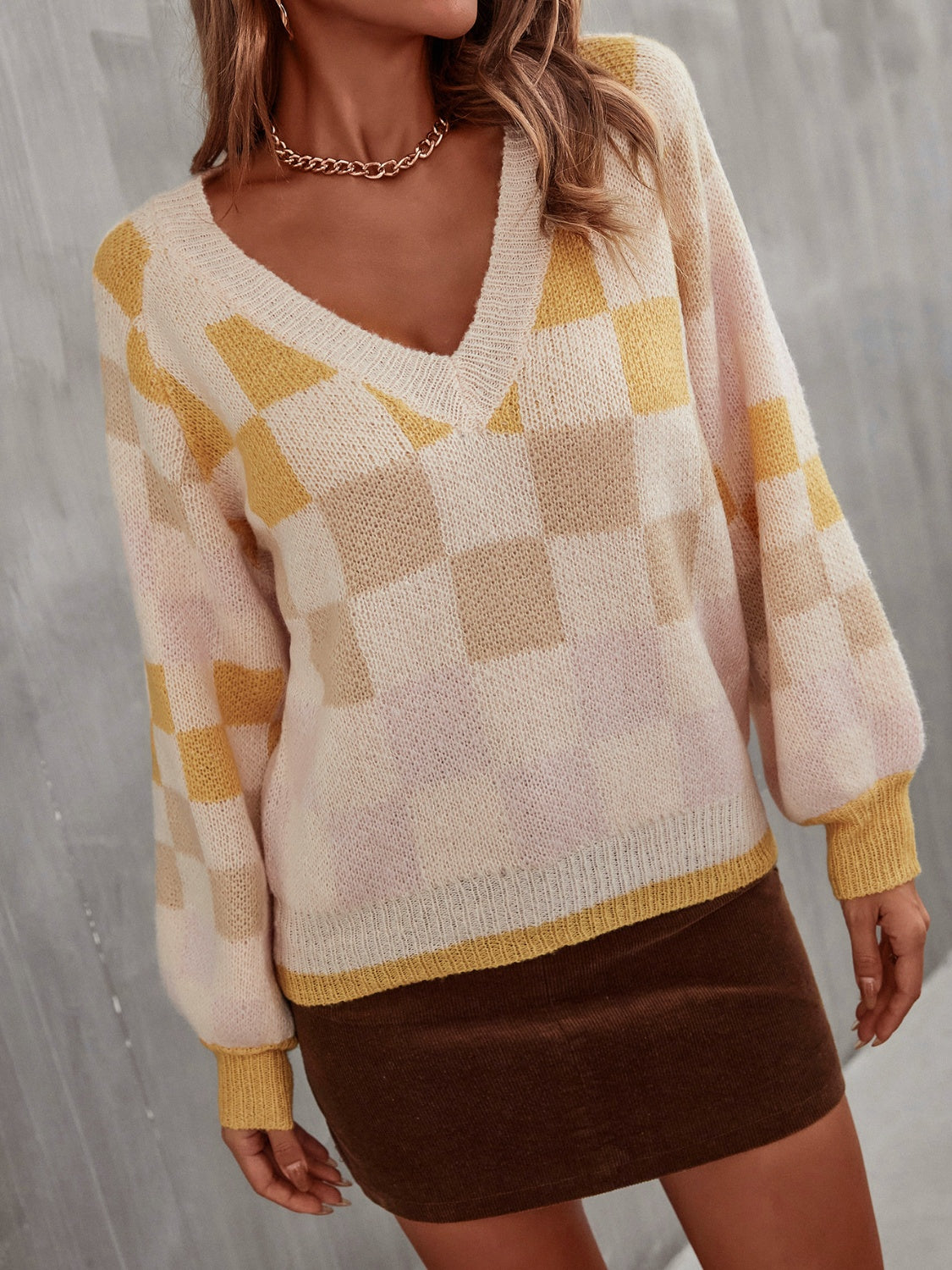 Trendy checkered v-neck sweater with lantern sleeves, perfect for a cozy and stylish look.